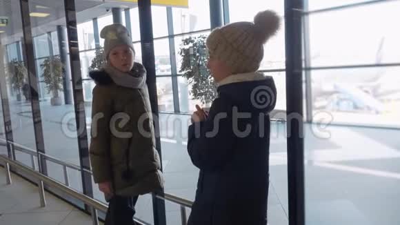 少女们在候机室等候飞机时看着机场窗口年轻女孩从飞机上视频的预览图