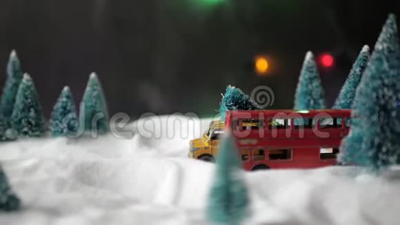 一辆小玩具黄色玩具车车顶有一棵圣诞树在一个带雪堆的小玩具森林里快速行驶视频的预览图