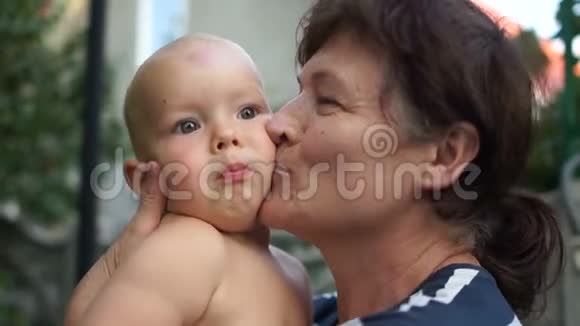 村里奶奶怀里的孩子成熟的女人温柔地吻她的小孙子视频的预览图
