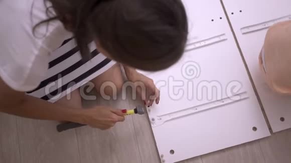 女孩收集一个盒子女性用螺丝刀收集白色木柜视频的预览图