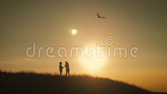 日落时两个孩子在田野里放风筝视频的预览图