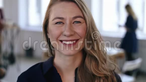 在时髦的现代办公场所摆姿势的快乐白种人金发商务女性的特写肖像欢快地笑着视频的预览图