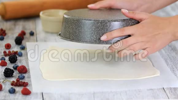 将面团切成圆形用于家庭烘焙女人用刀子在羊皮纸上切生面团视频的预览图