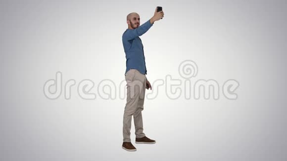 自拍时间英俊的年轻人在梯度背景上用手机自拍视频的预览图