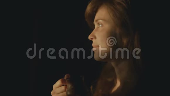 一个年轻的女人在窗前喝咖啡女孩的脸被夕阳照亮同时喝着一杯视频的预览图