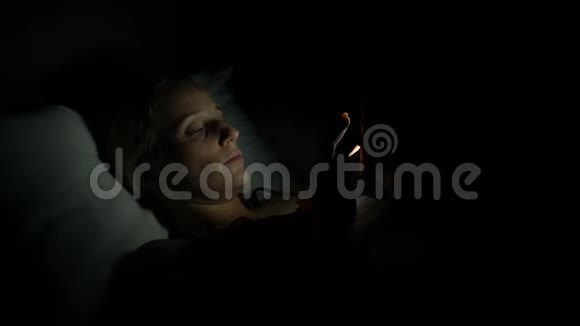 女人晚上躺在床上用智能手机视频的预览图