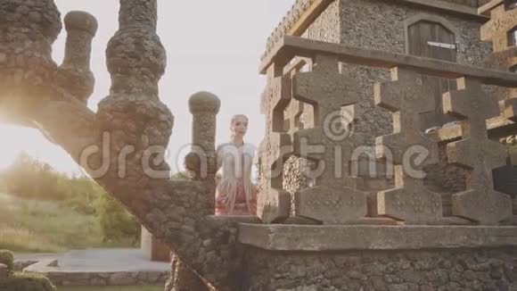 一身长得令人愉快的粉红色长裙镶着金色的花珠子放在大石台上视频的预览图