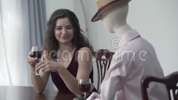 漂亮的卷发女人坐在桌边喝红酒帽子里戴着一个男模特模仿约会视频的预览图