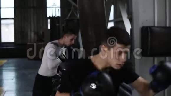 两名穿着休闲服装的白种人年轻男拳击手正在打黑拳梨努力工作培训过程视频的预览图