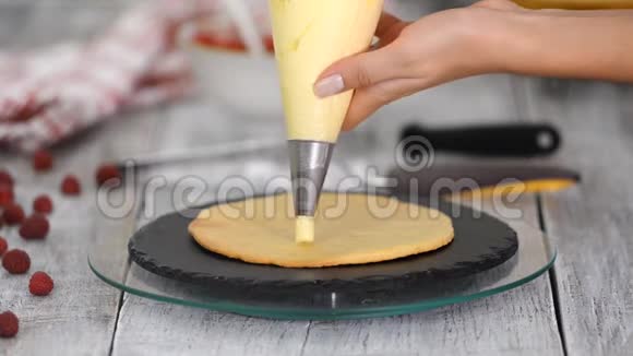 一个女孩在面包店做蛋糕面包师把奶油挤在蛋糕的空白上木桌上的白糕视频的预览图