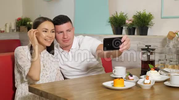 快乐的一对情侣坐在餐厅的餐桌上自拍视频的预览图