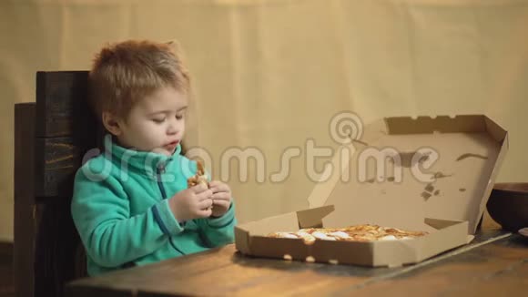 在木制背景下吃披萨的男孩美味的披萨小男孩在吃披萨饥饿的孩子咬一口视频的预览图