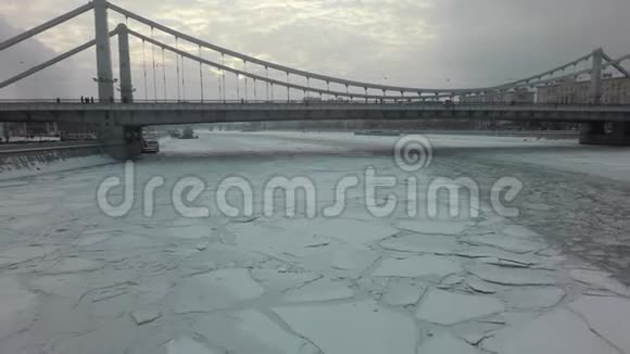 一条冰冻的河面和一座桥在冬季城市景观的中央视频的预览图
