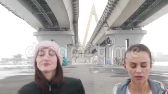 两个穿夹克的女人在桥下奔跑视频的预览图