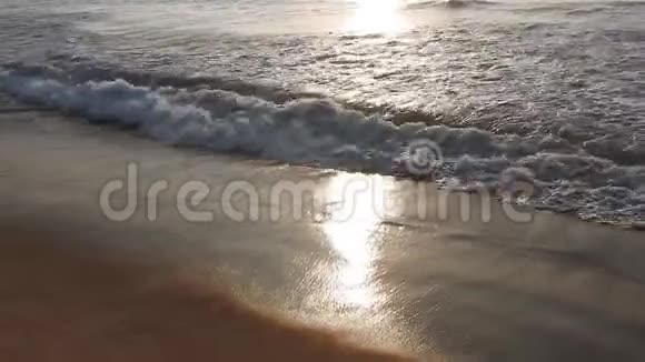 金色的阳光反射在海滩上太阳在傍晚照耀着海浪在岸边拍打海滩上的金色阳光视频的预览图