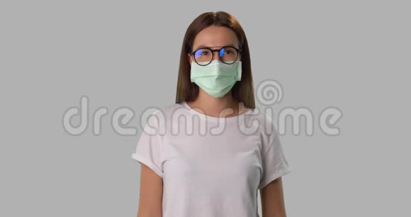 戴着口罩和眼镜的女人在白色的地方咳嗽视频的预览图