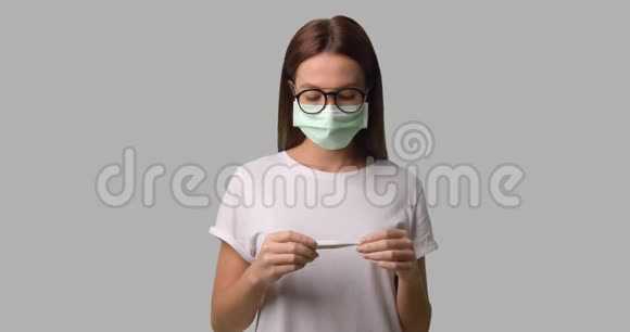 戴着医用口罩和眼镜检查体温的布鲁内特女士视频的预览图