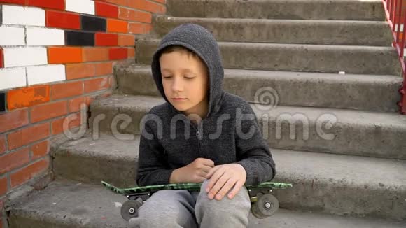 男孩坐在台阶上手里拿着滑板视频的预览图