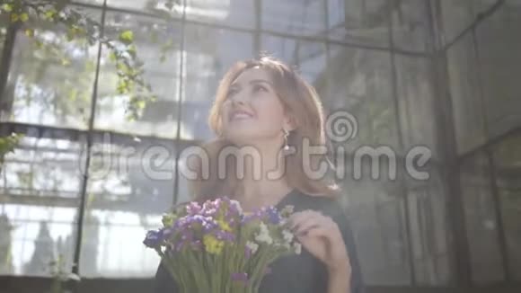 一幅美丽的年轻女子的肖像她拿着一束野花站在老楼上夏季概念视频的预览图
