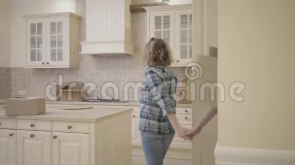长胡子的男人和漂亮的女人手牵手走进厨房一个人拿着盒子放在桌子上女人拥抱她视频的预览图