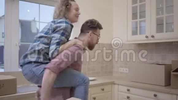 有胡子的男人背着漂亮的女人坐在厨房里女人拥抱丈夫指引丈夫走向视频的预览图