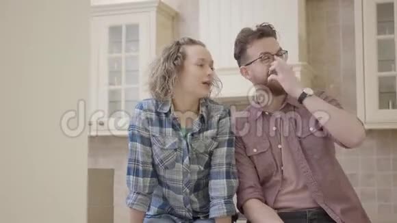 幸福的年轻夫妇坐在一间新公寓的厨房桌子上讨论房子的布局家庭搬迁视频的预览图
