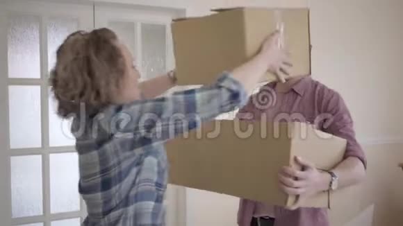 一对顽皮的夫妇站在门阶上的纸板箱一对年轻夫妇搬进了一个新家一家人玩得开心视频的预览图