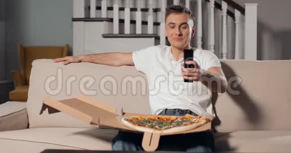 男子使用TV远程与披萨的Lap视频的预览图
