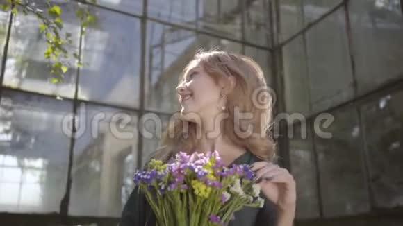 一位美丽的年轻女子的肖像她拿着一束野花站在老楼上夏季概念视频的预览图