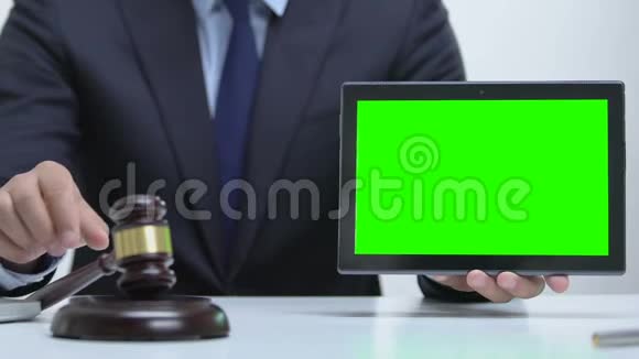男性手持绿色屏幕平板电脑用木槌敲击木块网络犯罪视频的预览图