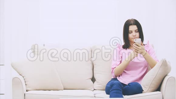 白人女孩坐在沙发上手里拿着电话发短信她的朋友加入她带来了很多视频的预览图