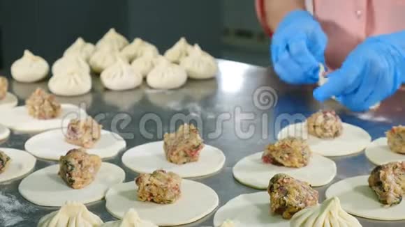 食物录像厨师长包肉饺子关门双手戴蓝色手套准备金属表面的饺子视频的预览图