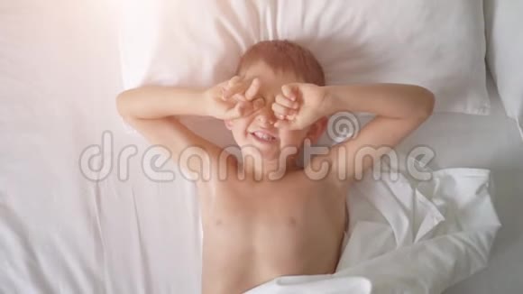 一个小男孩在床上打哈欠的俯视图视频的预览图