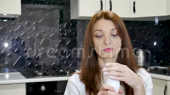 美丽的年轻女人喝酸奶手里拿着白色的瓶子健康饮食观念视频的预览图