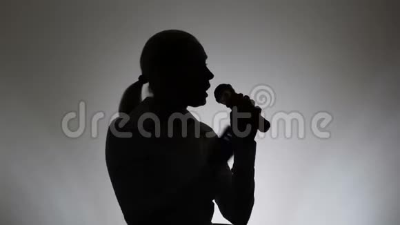 白色背景的女人的剪影一个女人在麦克风里唱歌视频的预览图
