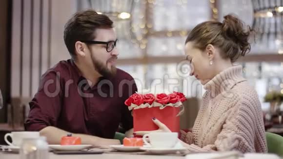 年轻夫妇坐在餐厅的桌子旁女人亲吻男人拿着花视频的预览图
