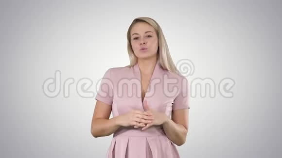 兴奋美丽的年轻女子穿着粉红色的连衣裙在渐变的背景上与相机交谈视频的预览图