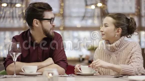 成年男子一边喝咖啡一边在餐馆里和女人说话视频的预览图