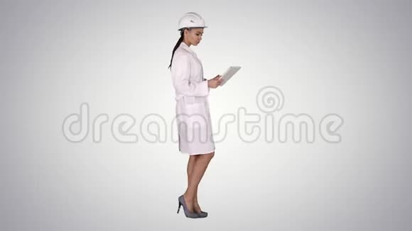 年轻的女工程师带着平板电脑走路在渐变背景下看着周围的物体视频的预览图