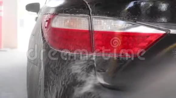专业工人正在洗车时用压力垫圈清洗一辆黑色汽车视频的预览图