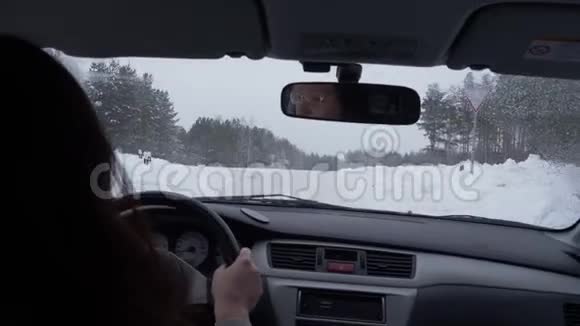 女子驾驶汽车在十字路和雪道冬季白天从后座观看视频的预览图