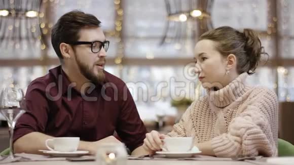 当服务员给他们端生寿司的时候年轻的男人和女人正在一桌一桌餐厅里交谈视频的预览图