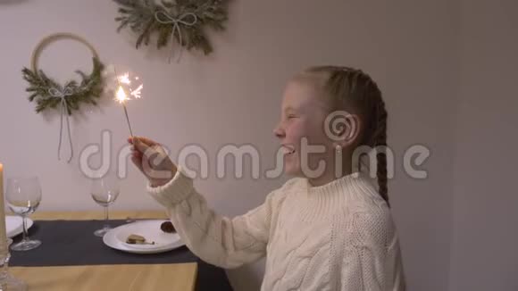 微笑的少女手持灿烂的火花坐在圣诞餐桌上视频的预览图