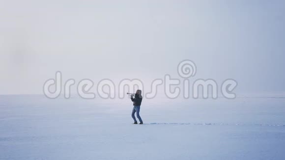白种人音乐家在冰冻的湖泊背景下积极而有感情地演奏小号视频的预览图