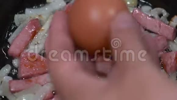 厨师把鸡蛋切成切片香肠和洋葱用油煎锅炒视频的预览图