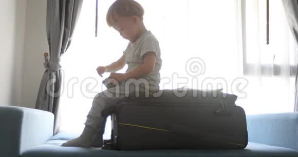 希尔德坐在手提箱上玩玩具车视频的预览图