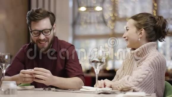 一位成年男子和一位漂亮女子正在餐厅餐桌旁进行滑稽的谈话视频的预览图