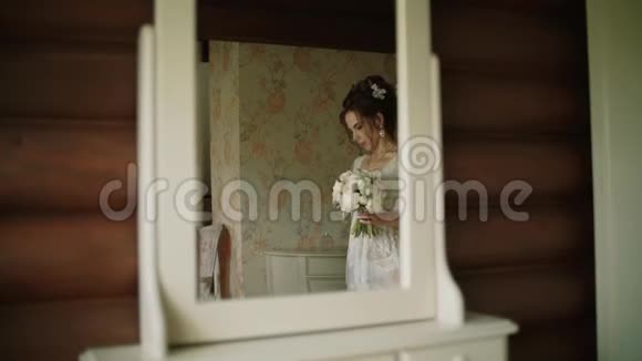 新娘穿着一件白色丝绸礼服在镜子里走着视频的预览图