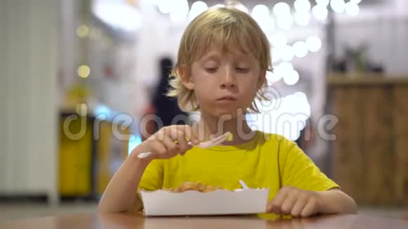 一个小男孩在街头咖啡馆吃美味的华夫饼的特写镜头街头食品概念视频的预览图
