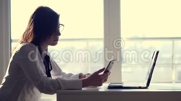 一位年轻的女职员办公室工作人员在她短暂的咖啡休息期间用手机浏览社交网络视频的预览图